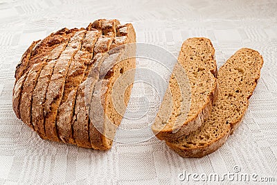 Sliced round loaf of rye bread with an appetizing crispy brown crust on a gray linen tablecloth. Tasty, usefull and nutritious. Stock Photo