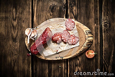 Sliced salami with garlic on a wooden trunk. Stock Photo