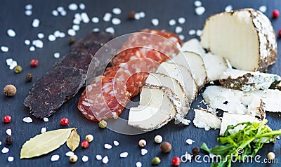 Sliced sausage with cheese and spised on a slate desck background. Stock Photo