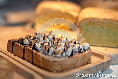 Sliced toasted bread with marshmello topping with chocolate sauce on wooden plate. Food and drinks concept. Bakery and coffee shop Stock Photo