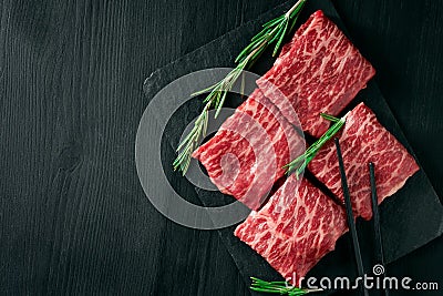 Sliced wagyu marbled beef for yakiniku on plate on black background, Premium Japanese meat and stick Stock Photo