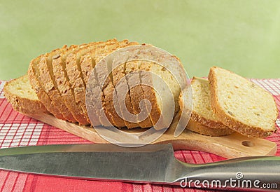 Sliced wheat bread on cutting Board closeup. Knife, red napkin Stock Photo