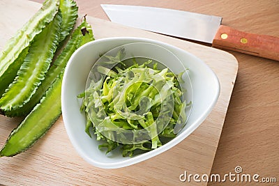 Sliced winged bean vegetable on the white dish and wooden block. Stock Photo