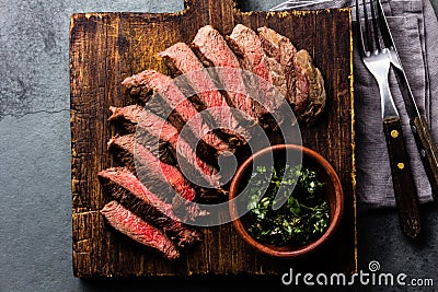 Slices of beef medium rare steak on wooden board, glass of red wine Stock Photo