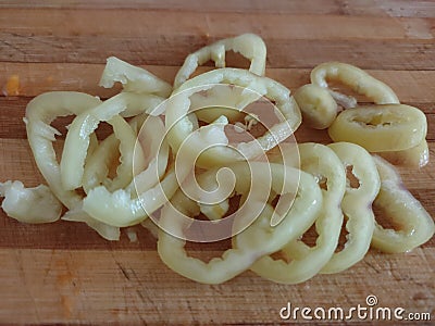 Slices of bell pepper on the wooden background in macro. Chopped bell pepper on a cutting board. Stock Photo
