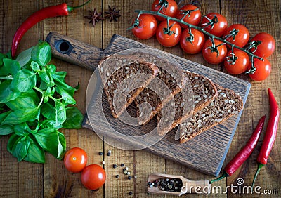 Slices of bread on a cutting Board, fresh tomatoes, fragrant Basil and hot pepper on a wooden table. Stock Photo