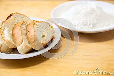 Slices of bread and wheat flour in a white plate on the table Stock Photo