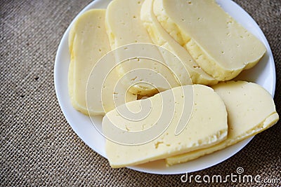 Slices of cheese cut on a plate. Delicious cheese with holes Stock Photo