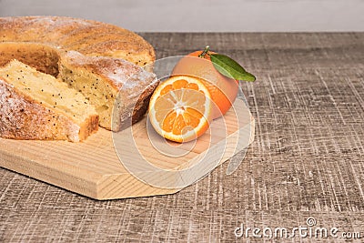 Slices of clementine cake with powdered sugar topping. Cake on a board with fresh clementines on wooden board Stock Photo