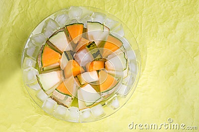 Slices different melon with ice on plate around green background. tasty sweet exotic fruit. flat lay Stock Photo