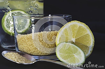 Slices of lemon and lime, cane sugar, spoon, glass Stock Photo
