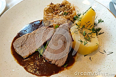 Slices of meat in a sauce with potatoes, greens, cabbage Stock Photo