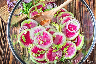 Slices pink fresh watermelon radish onion and celery homemade carpaccio salad for delicious breakfast on wooden table selective fo Stock Photo