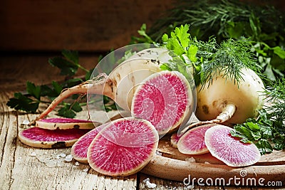 Slices of pink watermelon radish on a wooden table with parsley Stock Photo