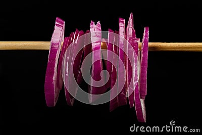 Slices of a purple onion hanging from a wooden stick Stock Photo