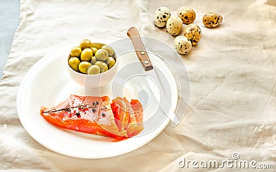 Slices of Salted Raw fish fillet with olive, quail eggs on white plate. Selection of good fat sources - healthy eating concept. Stock Photo