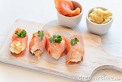 Slices of salmon wrapped with cottage cheese and marinated ginger. Party snack Stock Photo