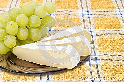 Slices of a soft cheese and white table grapes closeup Stock Photo