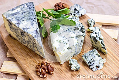 Slices and triangles of Danish Blue dorblue cheese with mold on a light paper background. Stock Photo