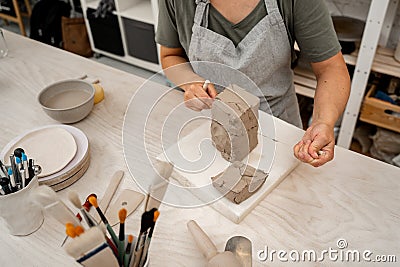 Slicing off a chunk of clay from a large block using a sharp wire clay cutter. Using a wire cutter to cut off a piece of Stock Photo