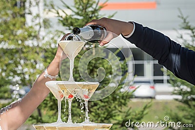 A slide of champagne. Pyramid of champagne glasses with red cherries. Stock Photo