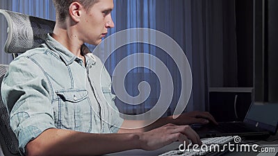 Sliding shot of a male freelancer working late in the evening using two computers Stock Photo
