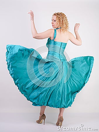 Slim airy girl in flying blue evening dress on white background in Studio Stock Photo