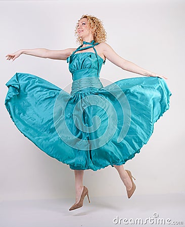 Slim airy girl in flying blue evening dress on white background in Studio Stock Photo