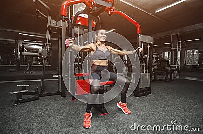 Slim, bodybuilder girl, does the exercises for arms in the gym Stock Photo