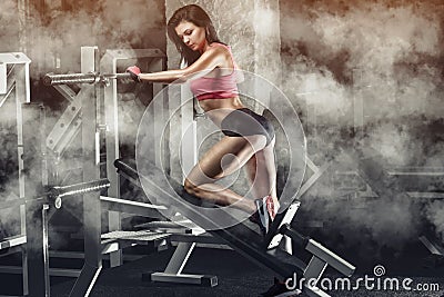 Slim, bodybuilder girl, does the exercises in the gym. Stock Photo