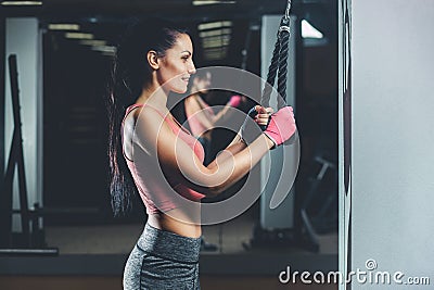 Slim, bodybuilder girl, does the exercises standing in front of the mirror in the gym. Stock Photo