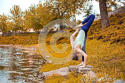 Slim brunette girl goes in for sports and performs yoga poses in the fall in nature by the lake Stock Photo