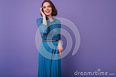 Slim debonair woman in long skirt posing with sincere smile. Indoor photo of shy beautiful girl tou Stock Photo