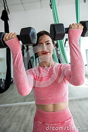 Slim female athletic doing exercises with dumbbells in fitness gym Stock Photo