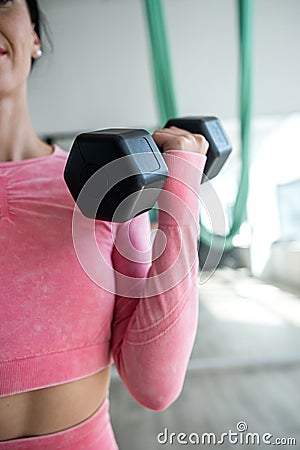 Slim female athletic doing exercises with dumbbells in fitness gym Stock Photo