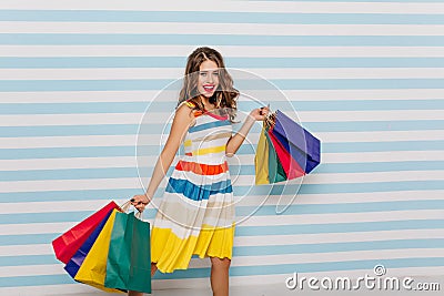 Slim glad woman smiling after shopping. Jocund caucasian girl holding new purchases from store.. Stock Photo