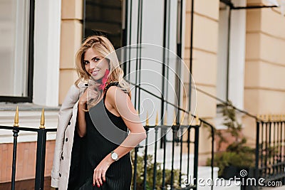 Slim glad woman in trendy white wristwatch laughing while posing beside store. Outdoor portrait of smiling female model Stock Photo