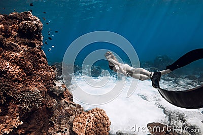 Slim woman in bikini swim with fins near coral reef in blue ocean. Freediving with sexy girl Stock Photo