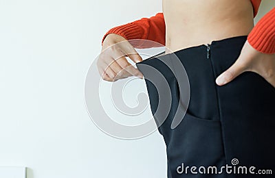 Slim woman with loose pants and showing successful weight loss,Female thin and slender body,Copy space on white blackground,Select Stock Photo