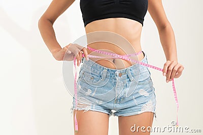 Slim woman measures her waist with measuring tape. Stock Photo