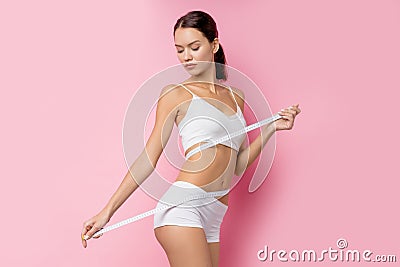 Caucasian woman with measurement tape over pink background Stock Photo