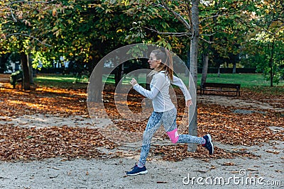 Slim woman with sportswear runs very fast in a park Stock Photo