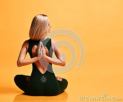 Slim woman trainer doing yoga pose asanas in sport fitness gym club in green sportswear on yellow with copy space Stock Photo