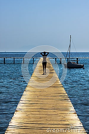 Slim woman walking along a jetty Stock Photo