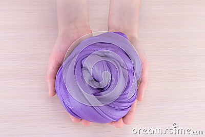 Slime in palms.Purple big glue,Close up of hands holding slime. View from above.Lght background Stock Photo