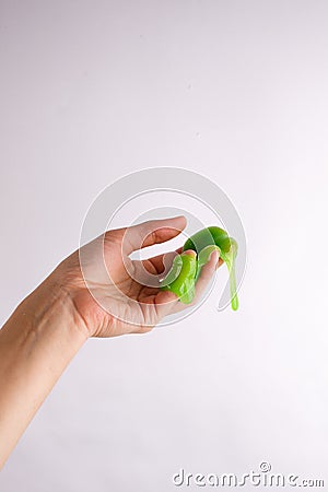 Slime paste green elastic and viscous, woman hand holding slime Stock Photo