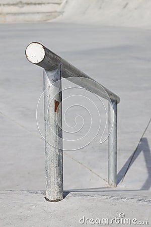 Sloped metal rail for grind tricks in an empty concrete skatepark Stock Photo