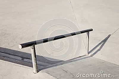 Sloped metal rail for grind tricks in an empty concrete skatepark Stock Photo