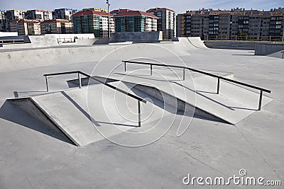 Sloped metal rails for grind tricks in an empty concrete skatepark Stock Photo