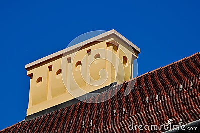 sloped red clay tile residential roof with decorative yellow stucco chimney. concrete capping Stock Photo